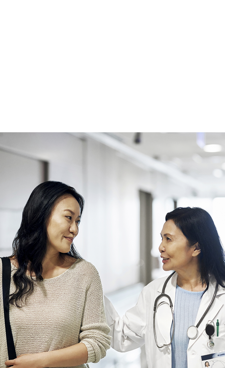 A healthcare professional walking down a hallway with a patient in a hospital setting.